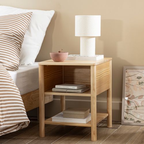 Petit meuble de nuit en bois clair avec lampe de chevet et livre posé sur le plateau