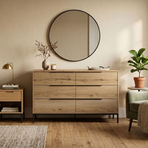 Commode 6 tiroirs en bois chêne Luce Terre de Nuit stylisée dans une chambre moderne.