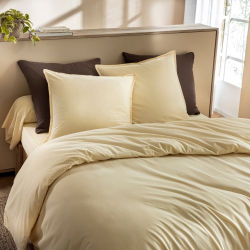 Lit douillet avec housse de couette coton lavé jaune dans une chambre lumineuse au style bohème