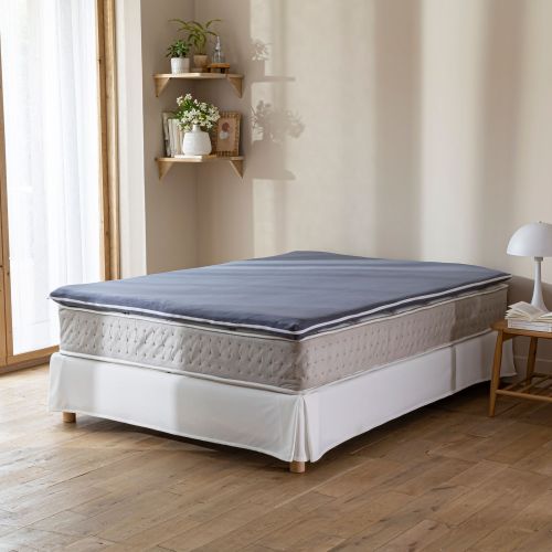 Lit double moderne avec une housse surmatelas en coton dans une chambre chaleureuse