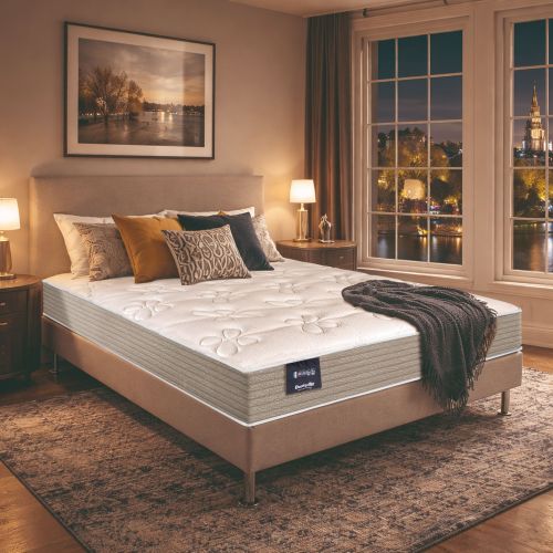 Matelas en ressorts ensachés ferme Dunlopillo Mimosa installé sur un sommier dans une chambre avec vue nocturne.