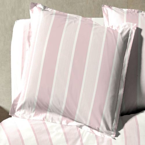 Deux taies d'oreiller aux rayures intemporelles posées sur un lit baigné de soleil