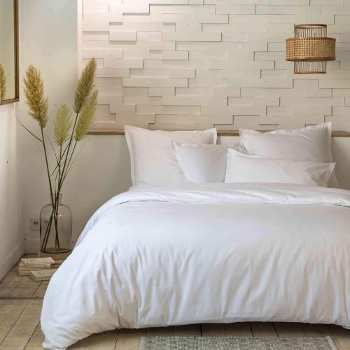 Parure de lit blanc percale unie installée dans une chambre lumineuse au style moderne et épuré