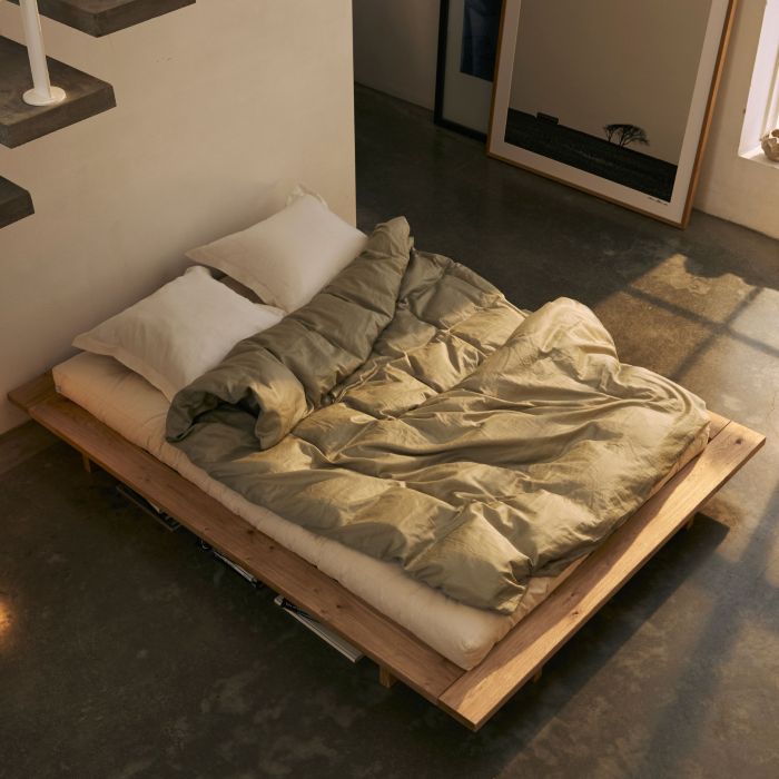 Lit futon bois chêne massif Karup Design Japan 2 personnes dans une chambre lumineuse.