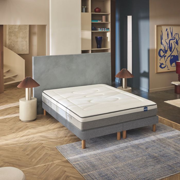 Matelas hybride ferme Bultex Restore posé sur un sommier dans une chambre moderne.