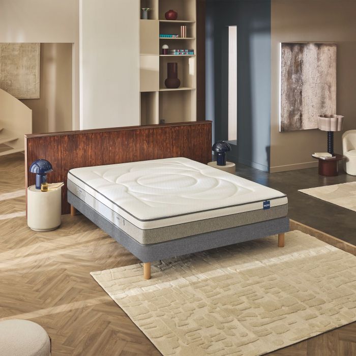 Matelas hybride ferme Bultex Move posé sur un sommier gris dans une chambre moderne.