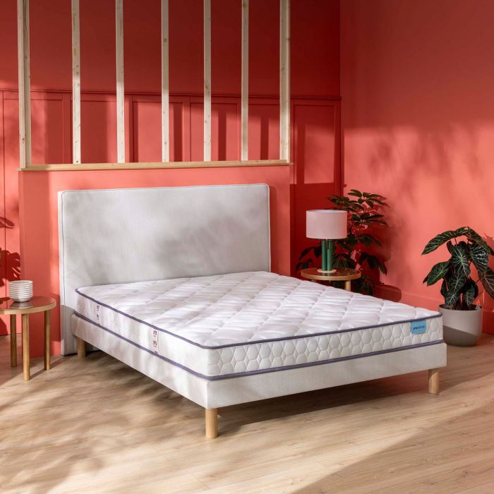 Matelas latex ferme Merinos Cosy Lit posé sur son sommier dans une chambre corail.