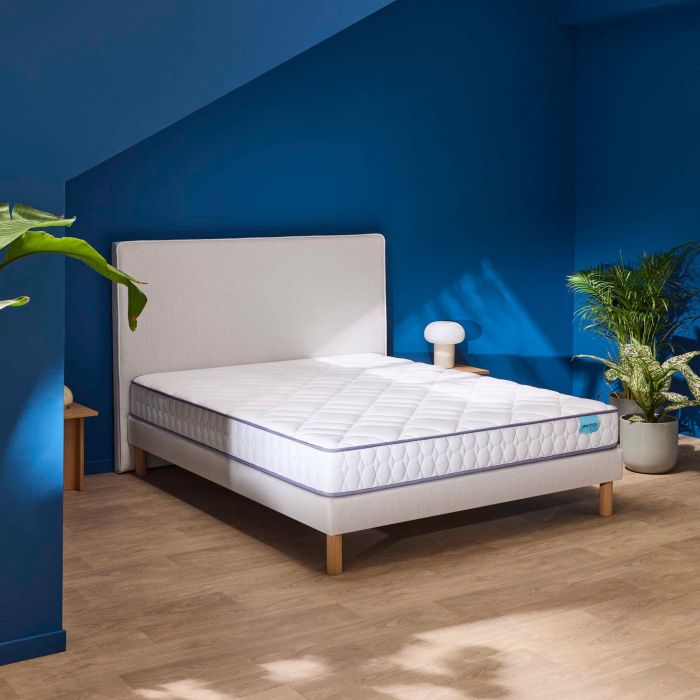 Matelas en mousse très ferme Merinos Chill Bed présenté dans une chambre moderne aux murs bleus.