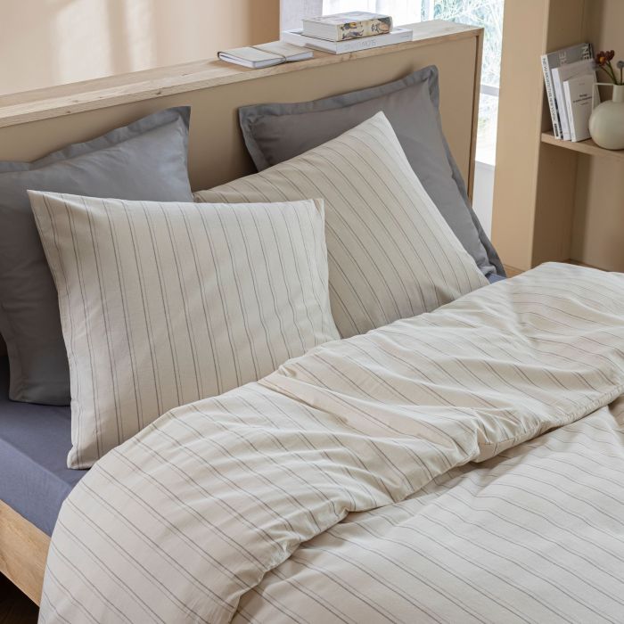 Parure Alba en coton écru à fines rayures grises sur un lit double moderne