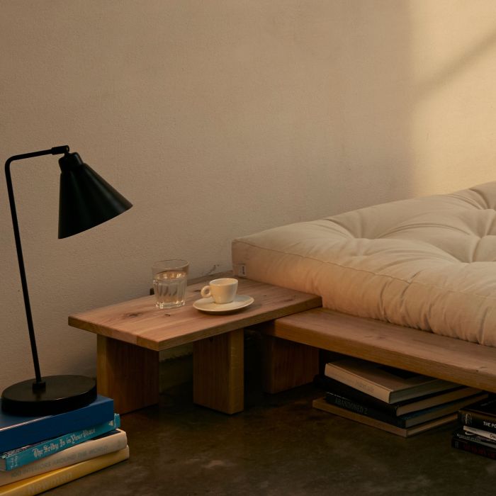 Table de chevet en chêne massif Karup Design aménagée près d'un lit futon.