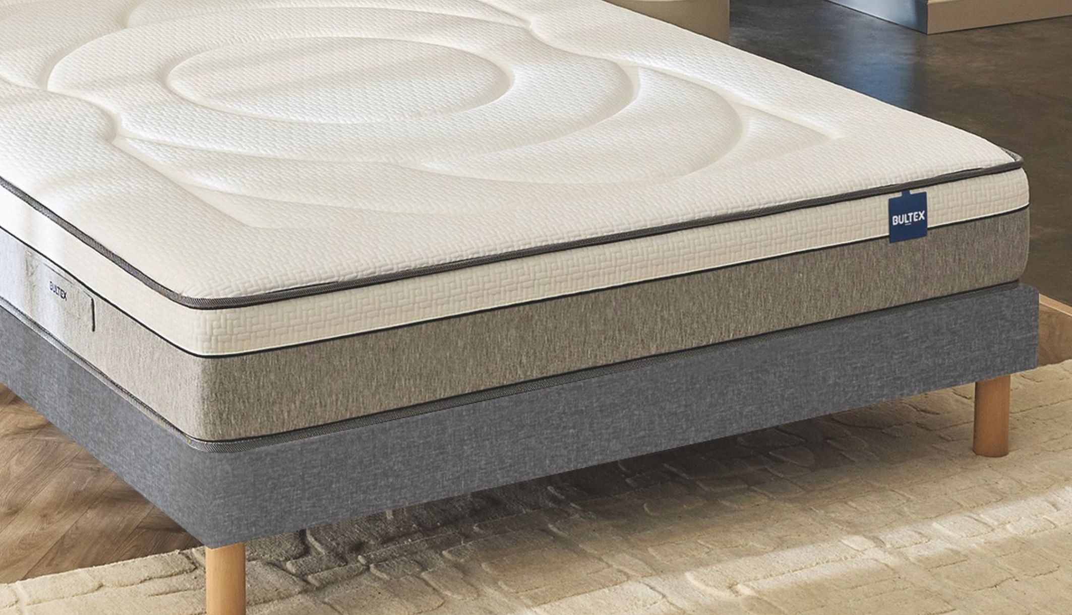 Vue détaillée de l&#039;épaisseur et des finitions du matelas hybride Bultex posé sur un sommier.