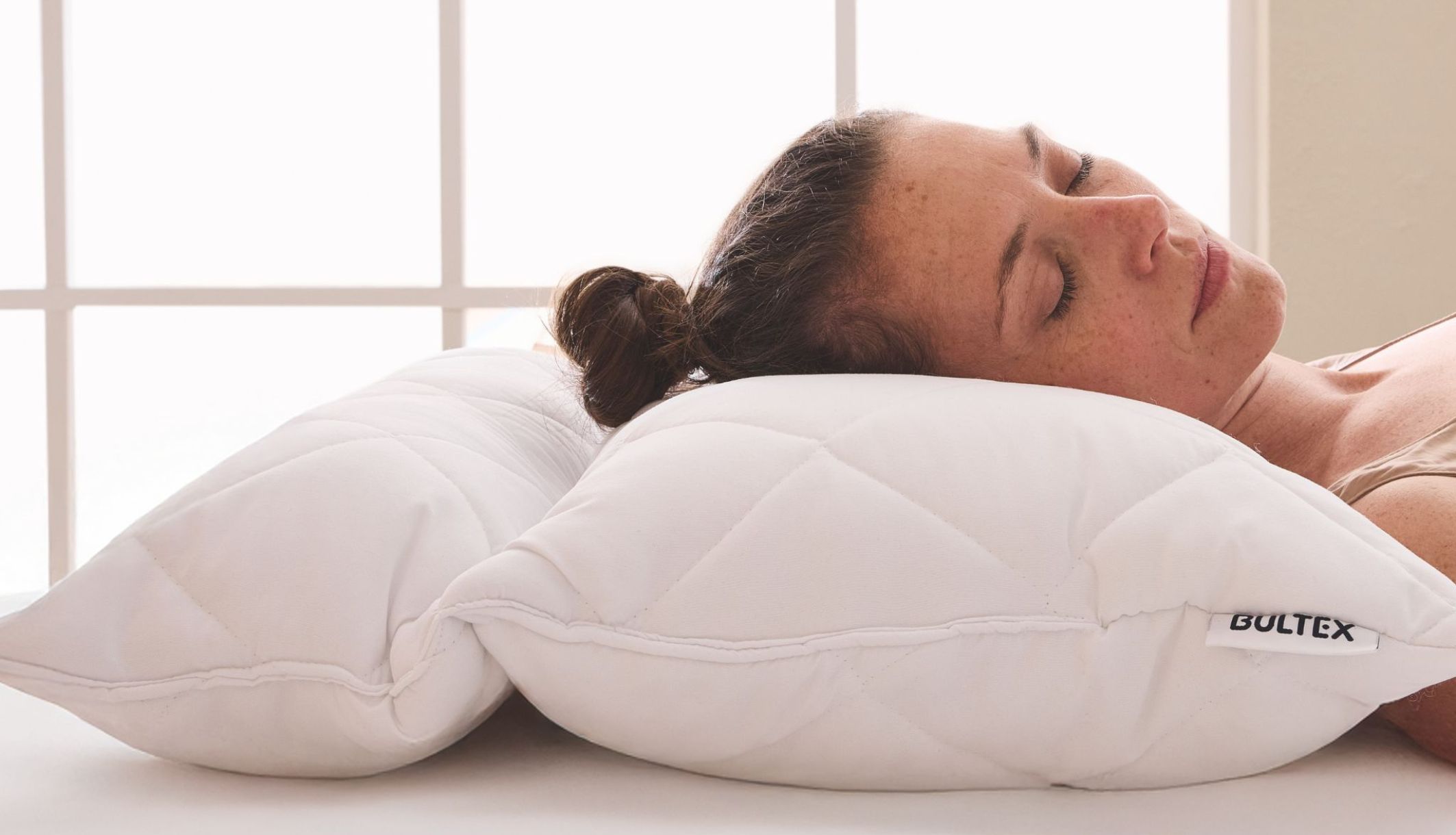 Femme dormant paisiblement sur l&#039;un des oreillers offerts matelassés de la marque Bultex.