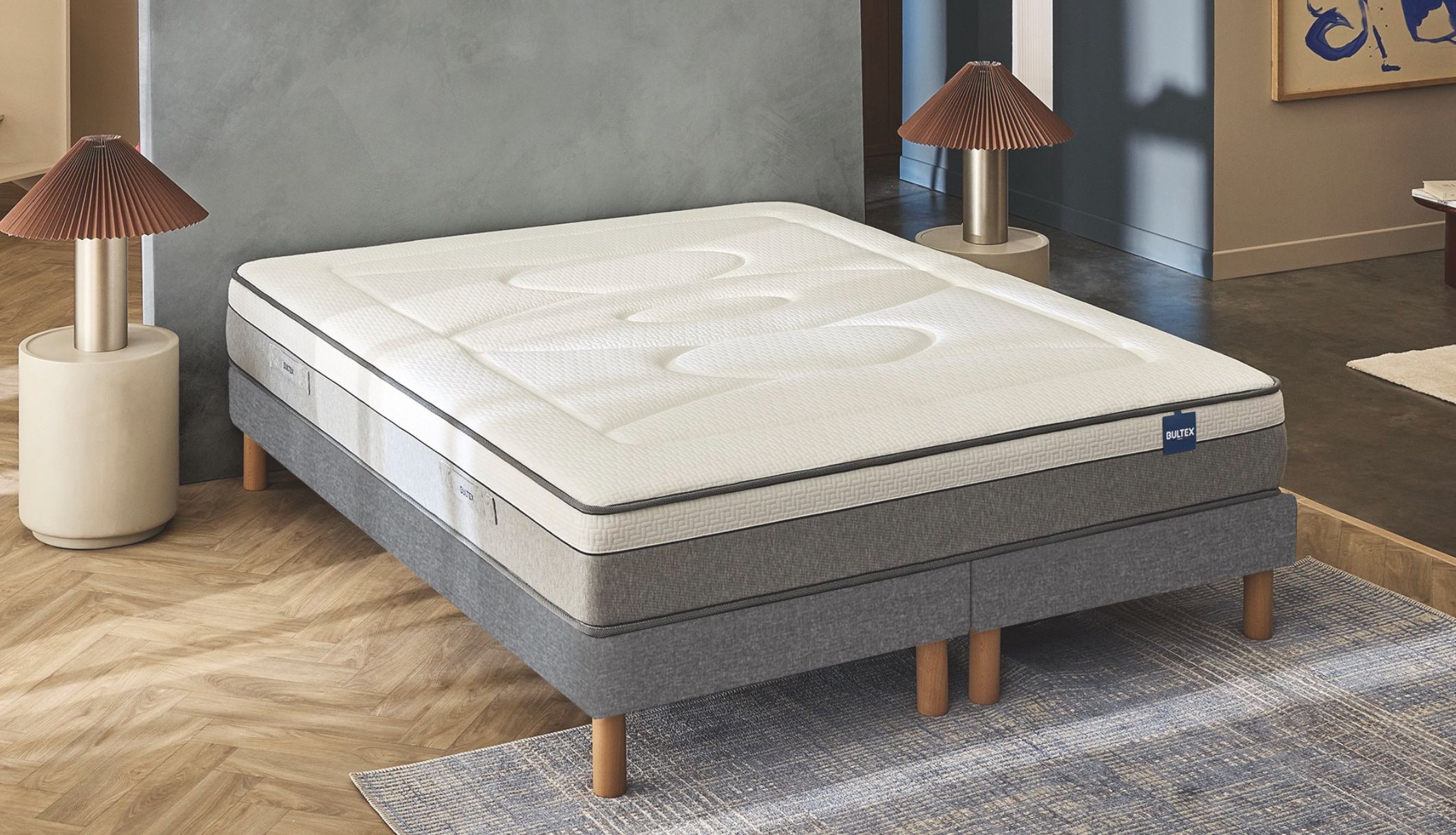 Matelas hybride Bultex Restore vu de 3/4 sur son sommier dans une chambre élégante.