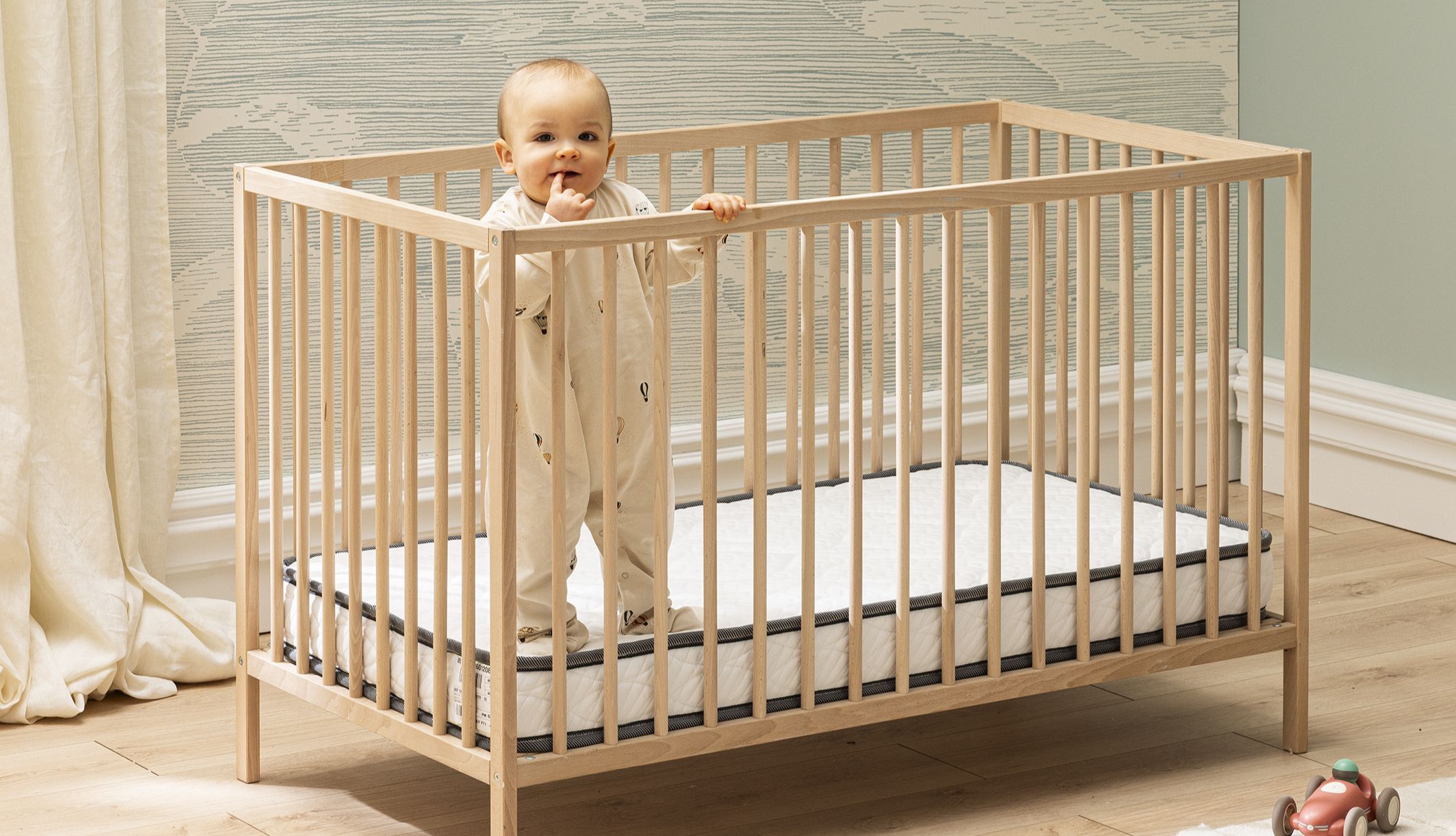 Bébé dans son lit en bois sur le matelas bébé en mousse ferme Bultex Tichou.