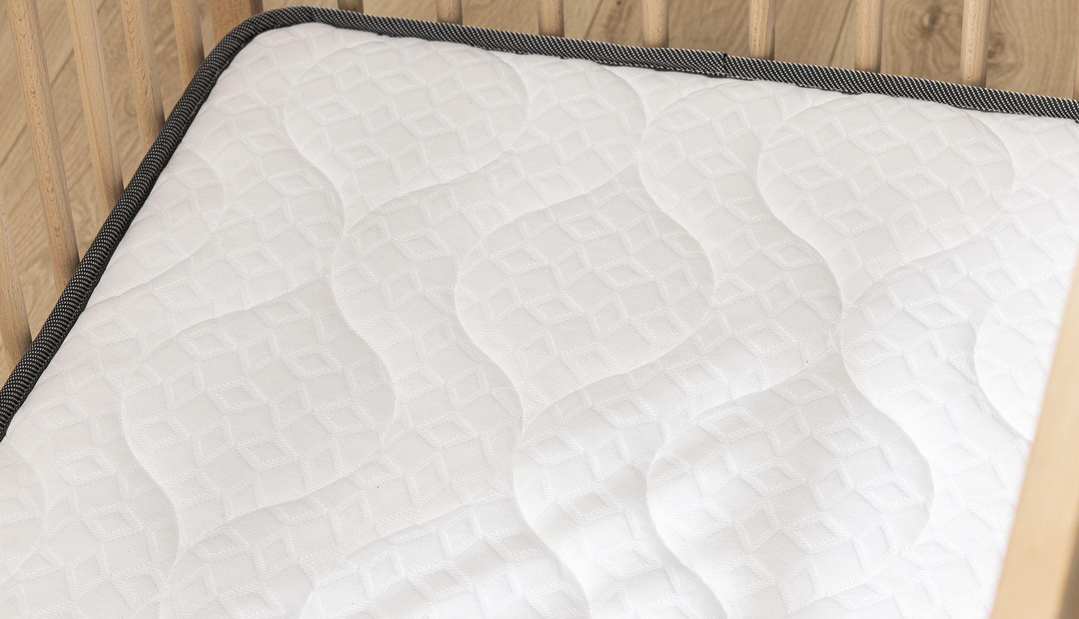 Gros plan sur les finitions et le coutil matelassé du matelas lit bébé.
