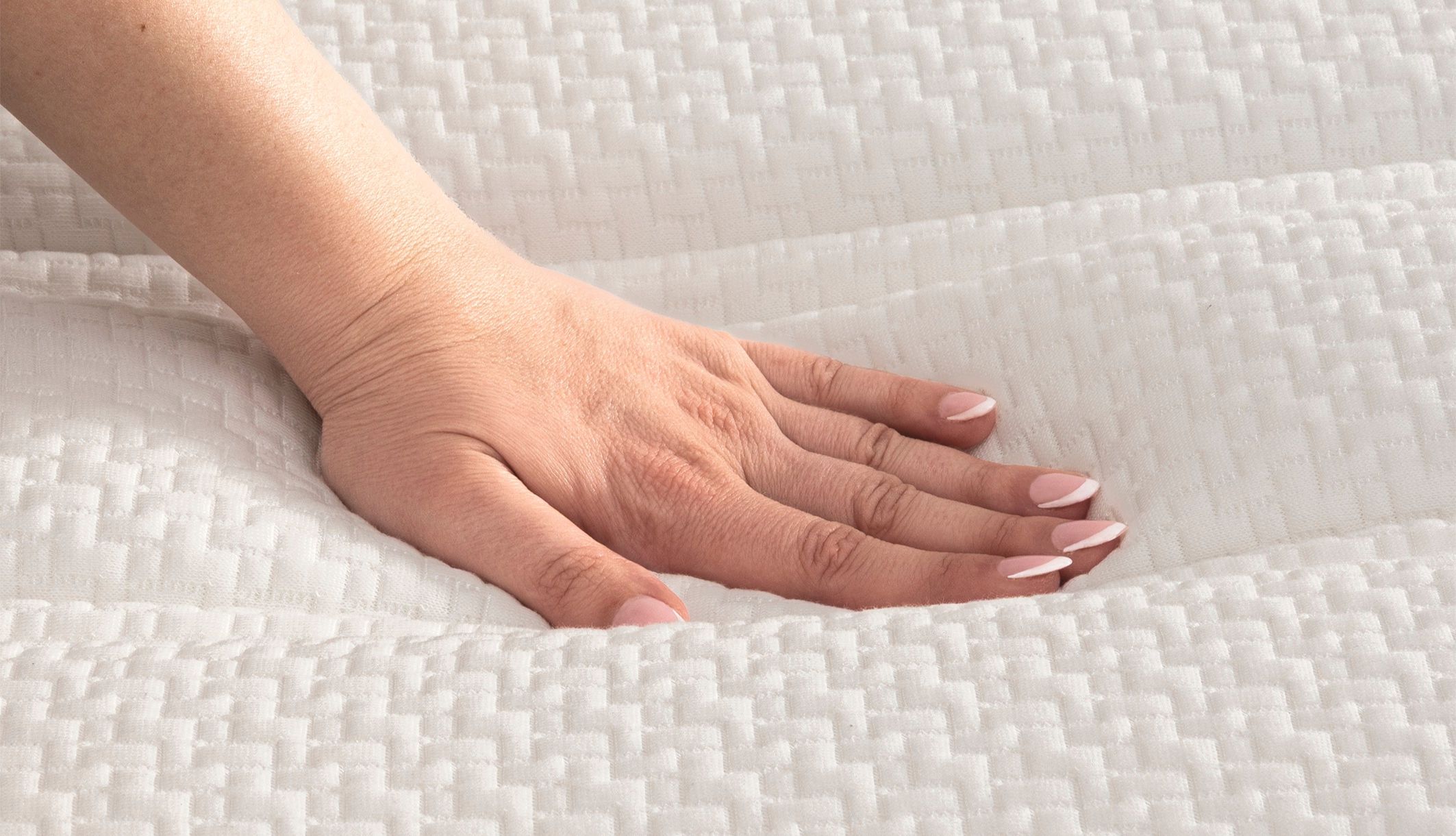 Main testant le moelleux et le coutil texturé du matelas Bultex relaxation.