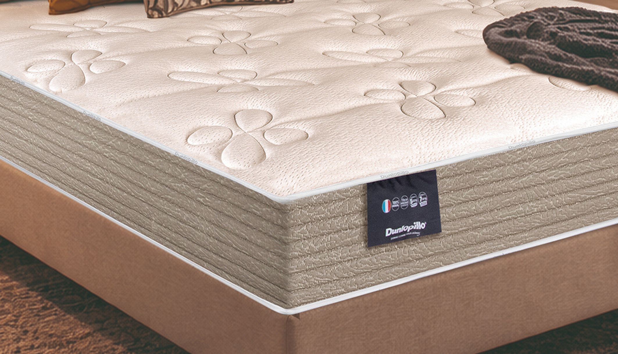 Zoom sur le coutil fleuri et l&#039;étiquette du matelas ferme en ressorts ensachés Dunlopillo Mimosa.