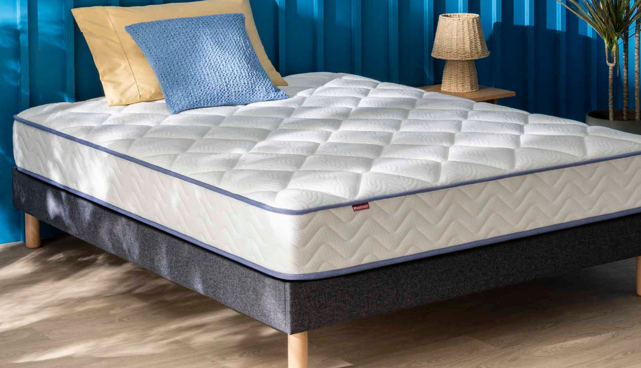 Matelas ressorts ensachés et mémoire de forme Merinos Sweety sur un sommier gris.