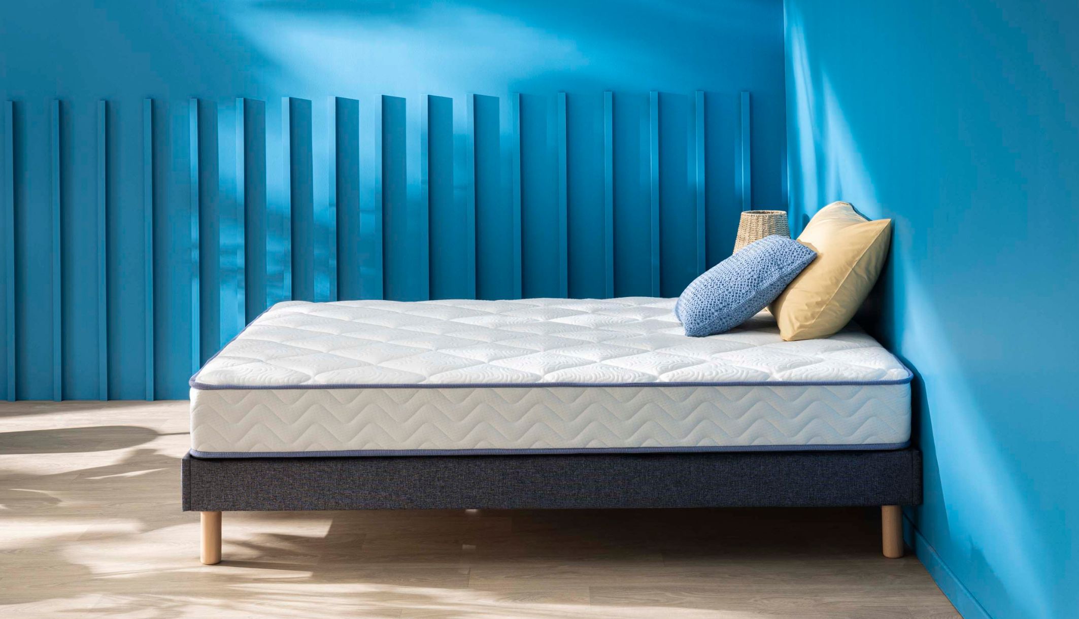 Matelas ressorts et mémoire de forme Merinos Sweety, profil avec coussins décoratifs.