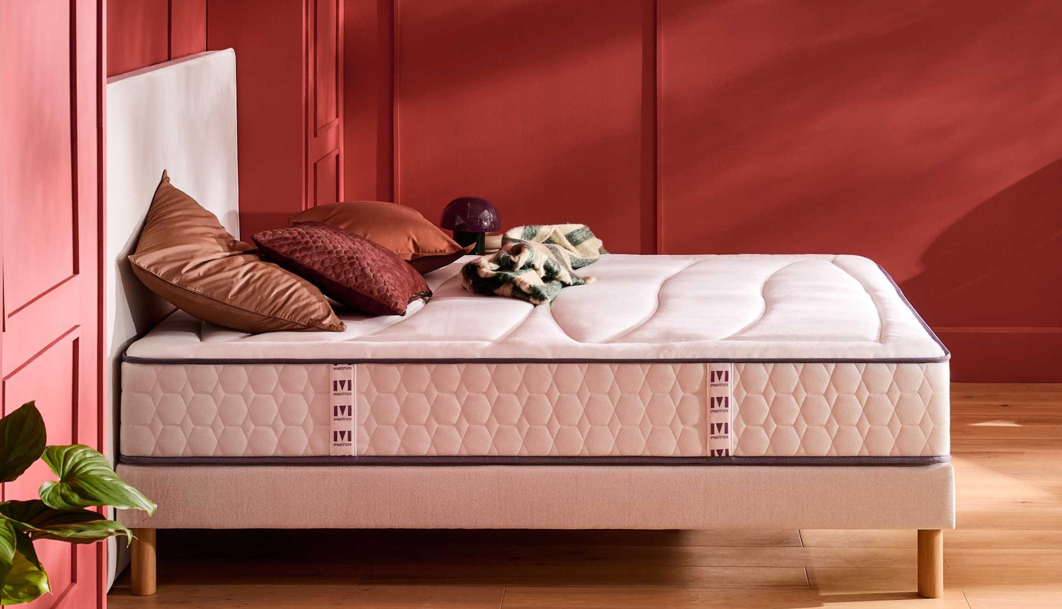Matelas ressorts ensachés et mémoire de forme Merinos Beauty Bed dans une chambre moderne rouge.
