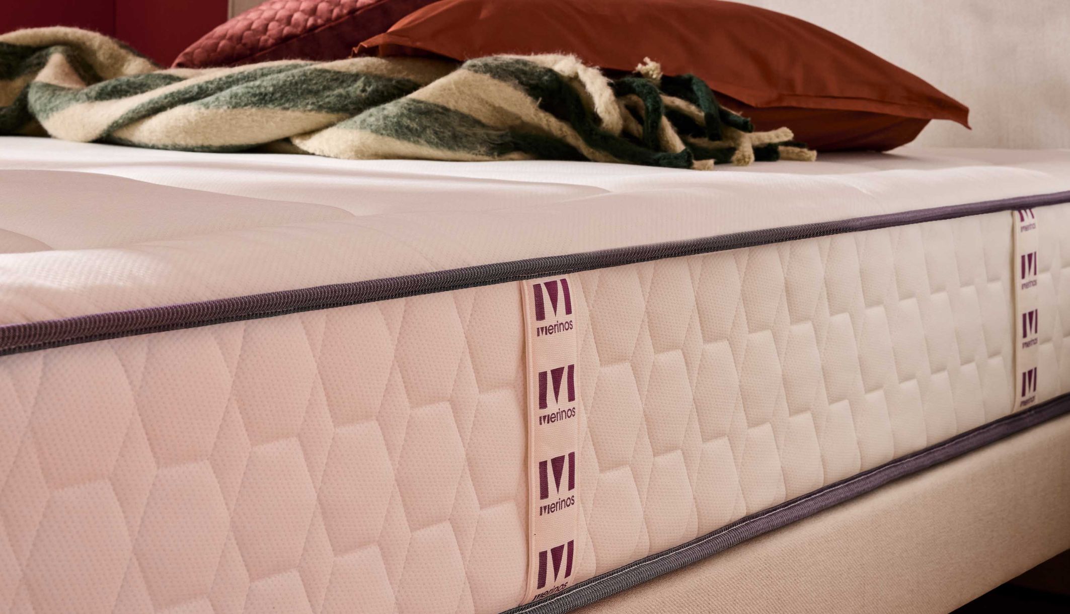 Finitions latérales et poignées brodées du matelas Merinos à ressorts et mémoire de forme.