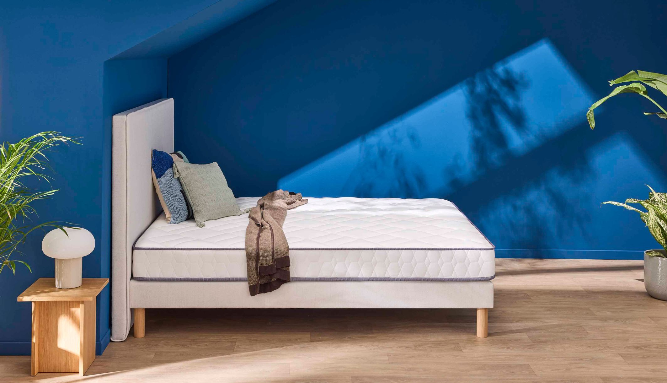 Vue latérale du matelas en mousse très ferme Merinos Chill Bed dans une chambre bleue.
