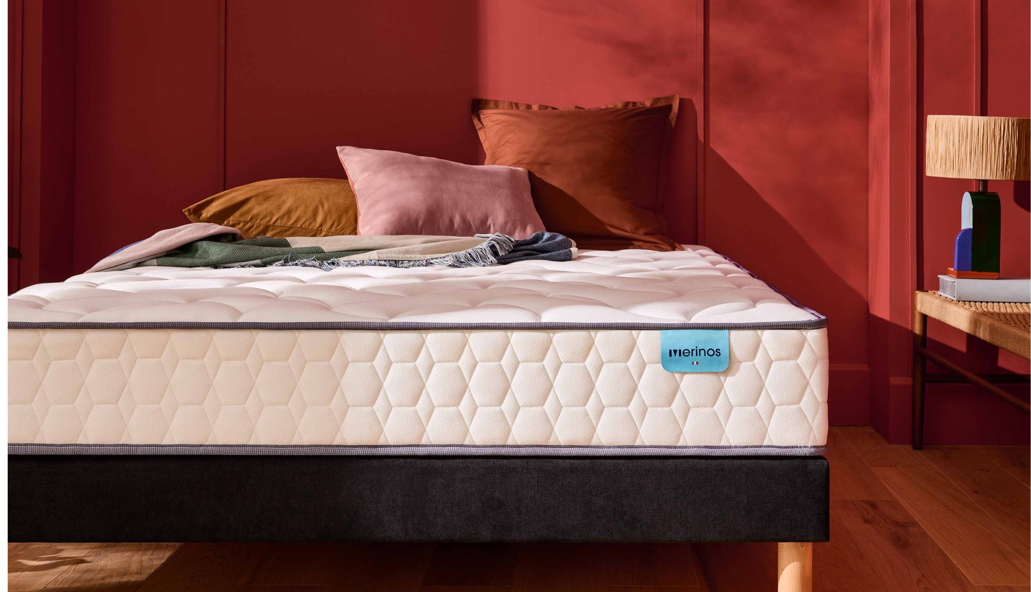 Matelas ressorts ensachés très ferme Merinos Cosy Lit posé sur un sommier tapissier noir.