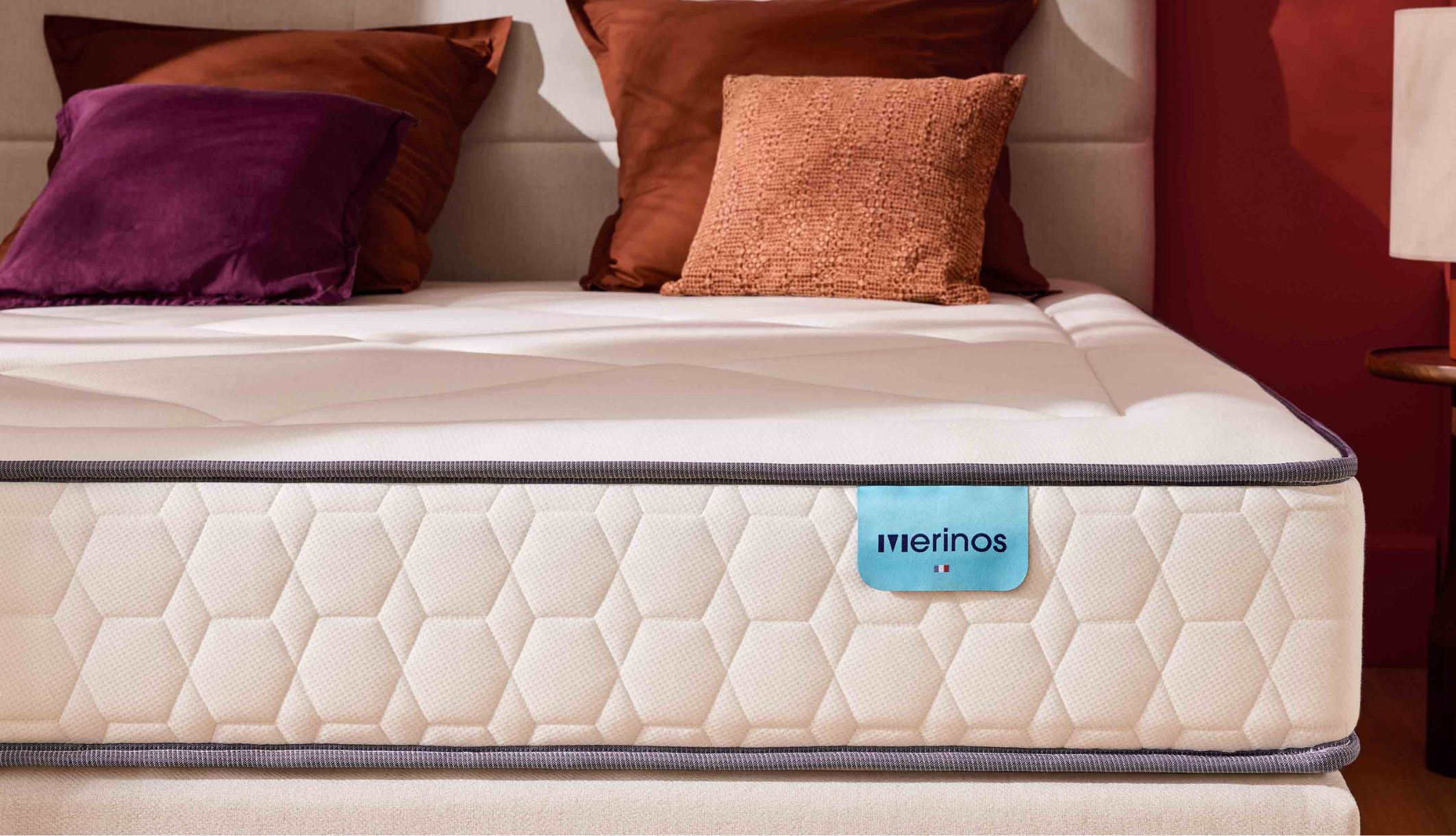 Zoom sur le coutil alvéolé blanc et l&#039;étiquette bleue du matelas Merinos Full Bed.