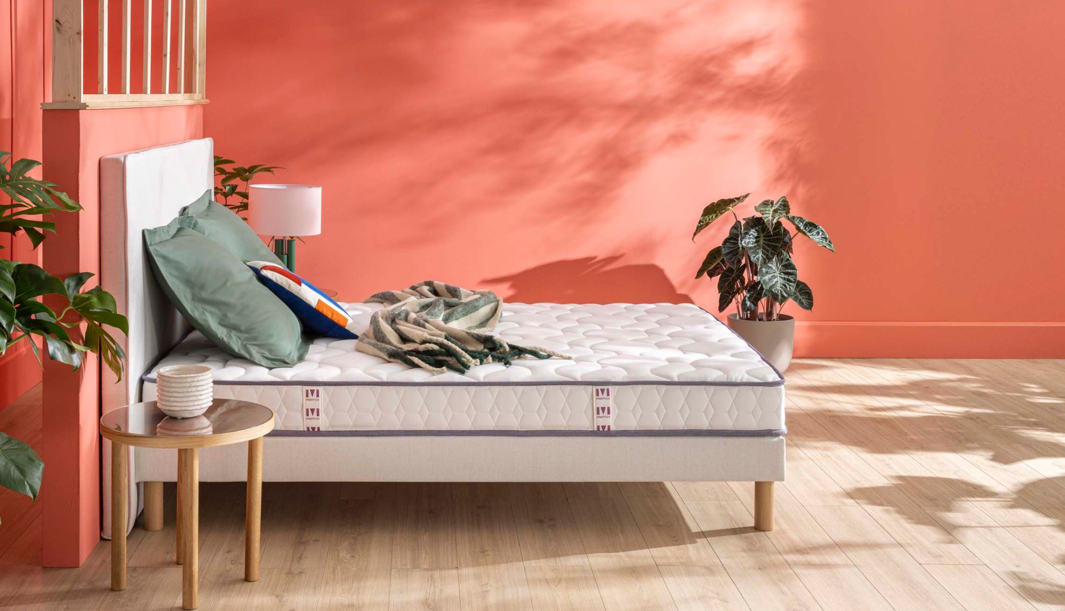 Matelas latex ferme Merinos Cosy Lit installé sur un sommier dans une chambre corail.