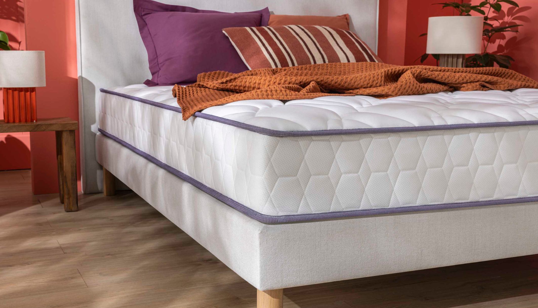 Matelas ferme Merinos avec coutil texturé alvéolé posé sur un sommier tapissier blanc.