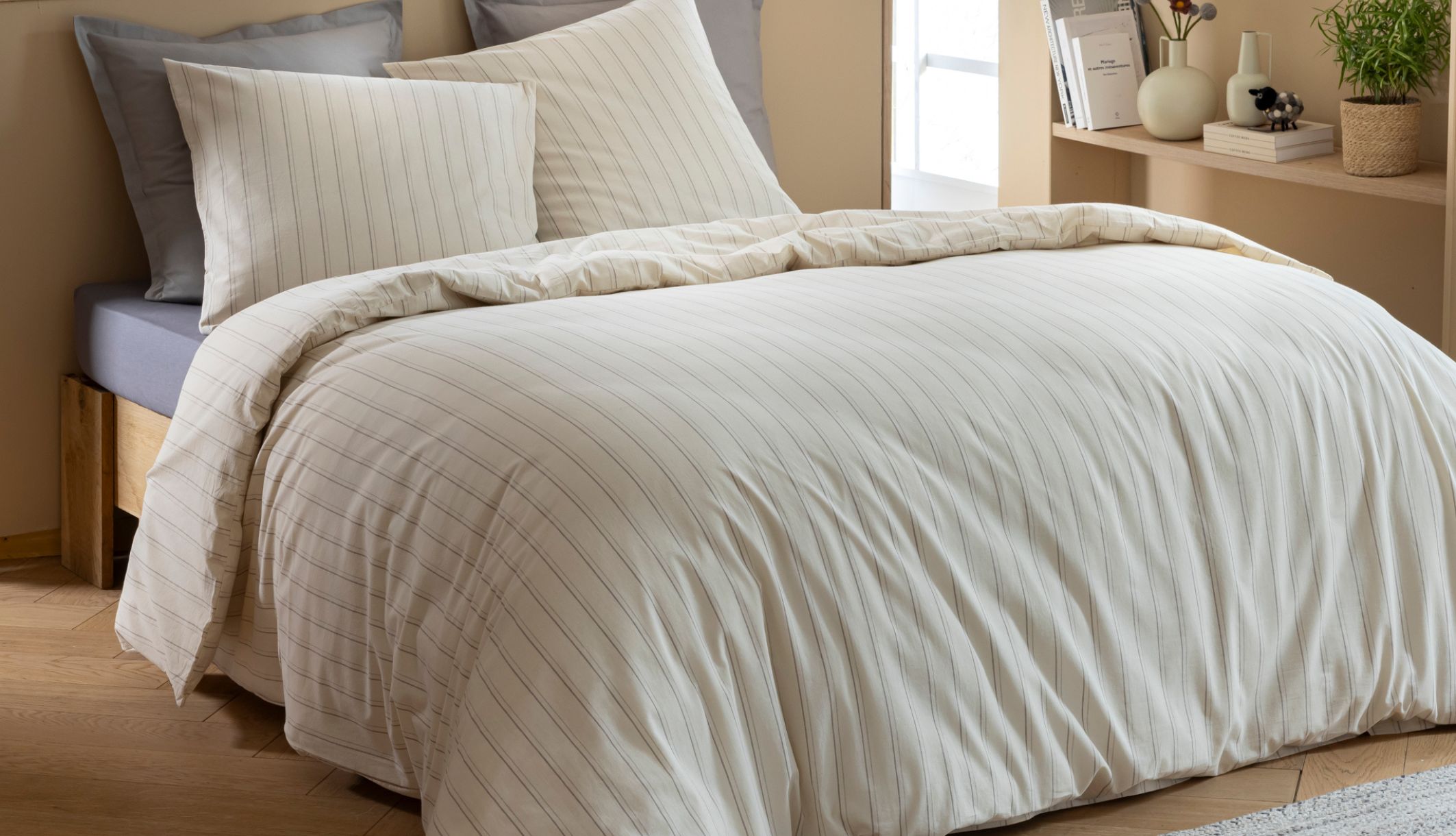 Parure Alba en coton écru à fines rayures grises sur un lit double moderne