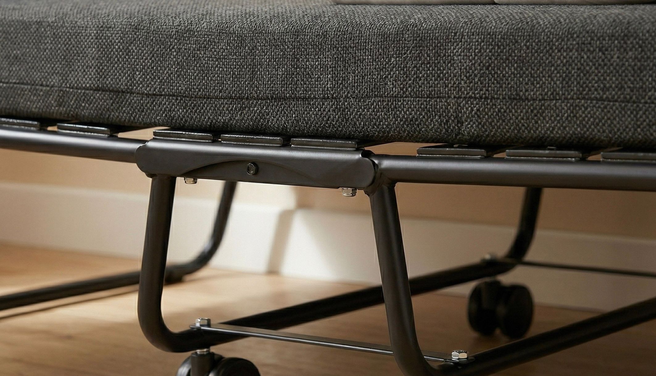 Zoom sur le sommier à lattes et les roulettes du lit pliant 1 personne robuste.