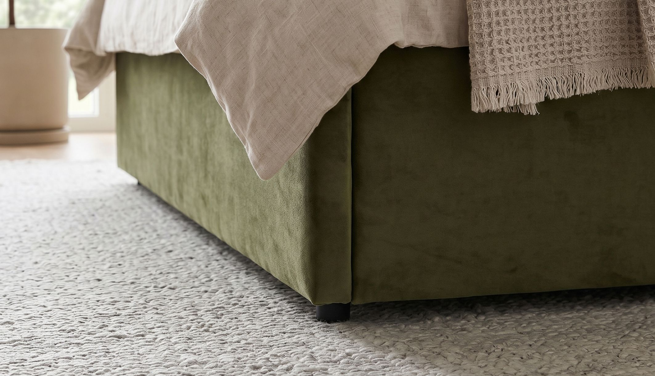 Zoom sur le bas du lit coffre en velours avec les pieds en PVC 