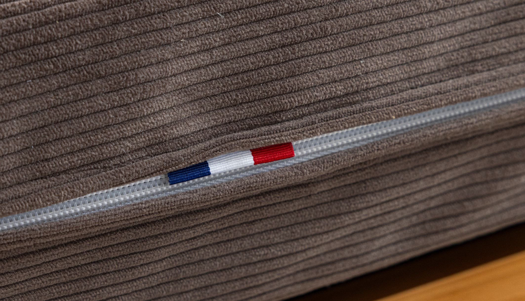 Détail du capitonnage et de l&#039;étiquette fabrication française sur le tissu velours côtelé chocolat.