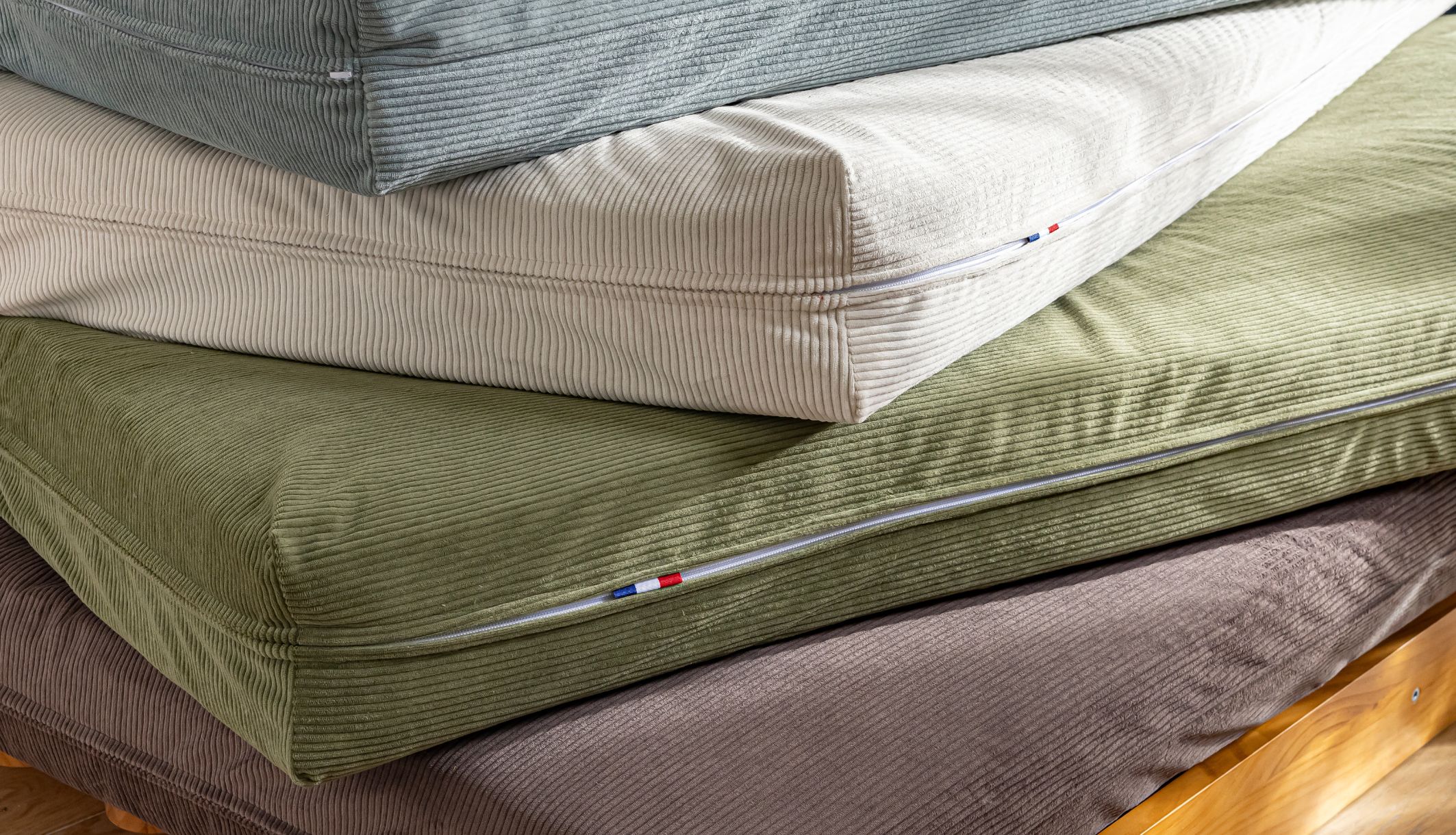 Empilement de matelas futon révélant les couleurs du velours côtelé et l&#039;étiquette française.