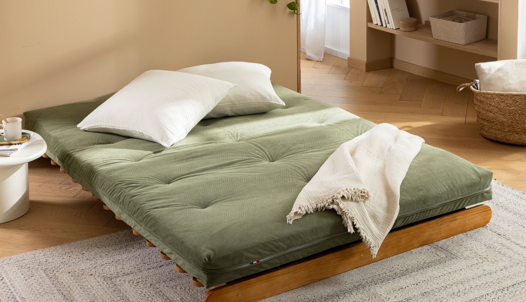 Matelas futon déplié à plat avec coussins, mettant en valeur son revêtement en coton.