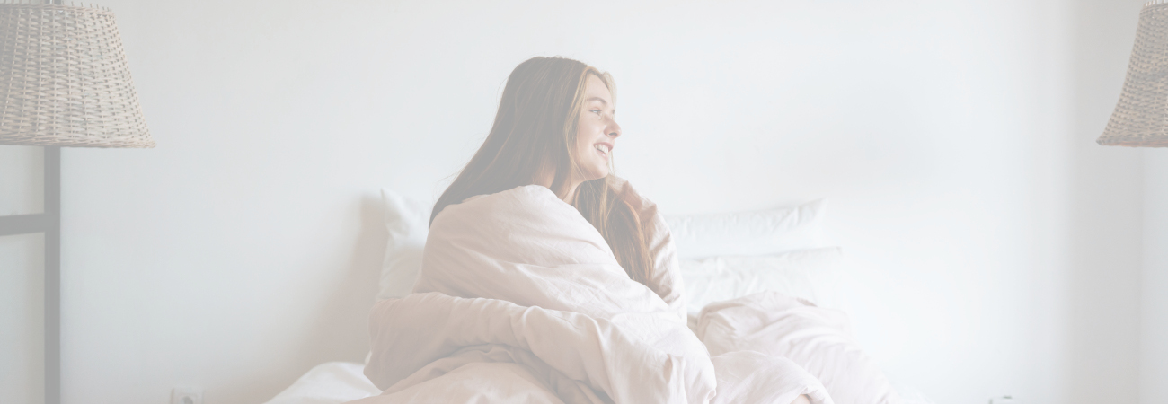 femme souriante assise sur son lit