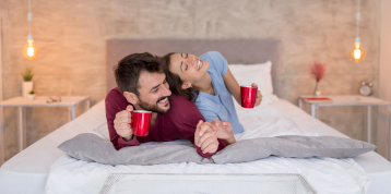 couple heureux couché avec tasses rouges dans les mains