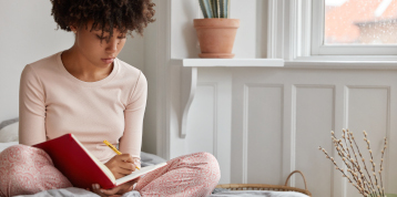 femme assise sur lit avec journal intime