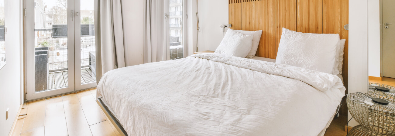 grand lit blanc avec tête de lit en bois